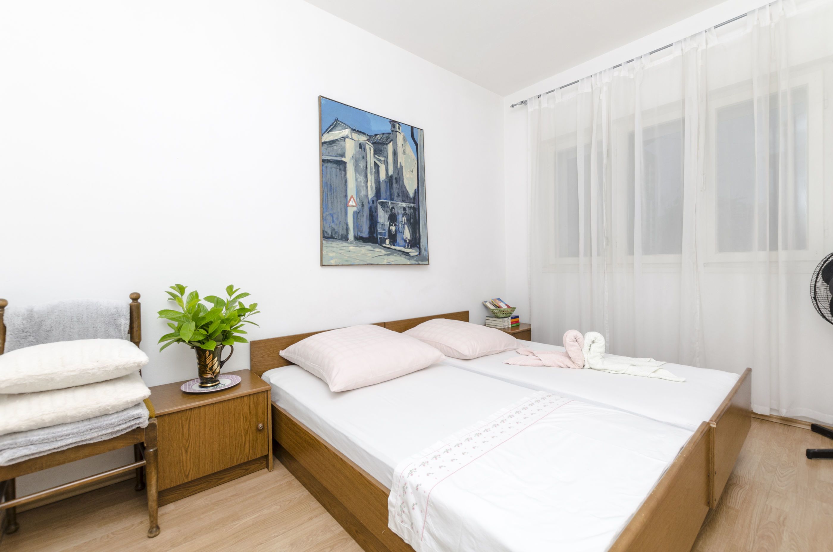 Una camera da letto ordinata con un letto, un comodino e un quadro appeso al muro.