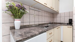 A kitchen with a marble countertop, a sink, a coffee maker, and a vase of flowers on the counter.