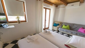 A hotel room with two beds, a sofa, a TV, and a window with curtains.