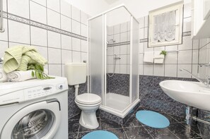 Un bagno moderno con lavatrice, vaso, doccia e lavandino.
