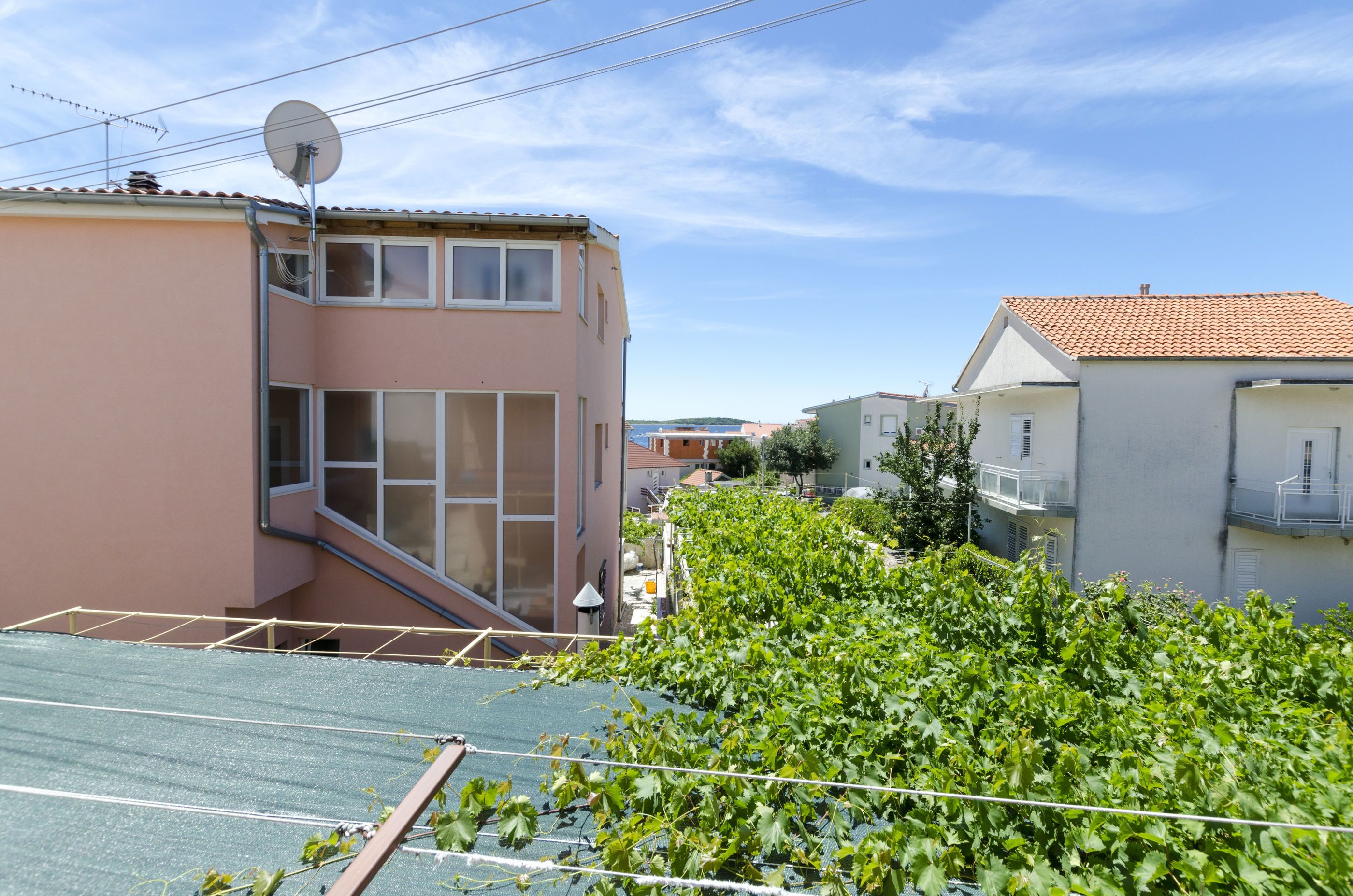 Ein Wohngebäude mit Satteldach, Satellitenschüssel und einem Gartenbereich mit Grünpflanzen.