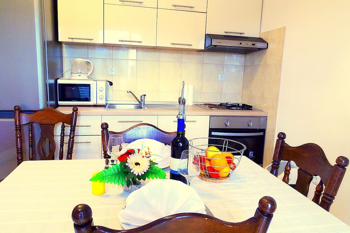 A dining table set with a bottle, glasses, and a fruit basket.