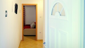 A hallway with a door marked '2', a bed with a red blanket, and a small window. - Apartments Graciela (Zaklopatica)