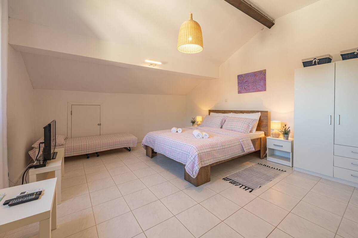 A bedroom with a bed, bedside table, lamp, wardrobe, and a desk with a computer.