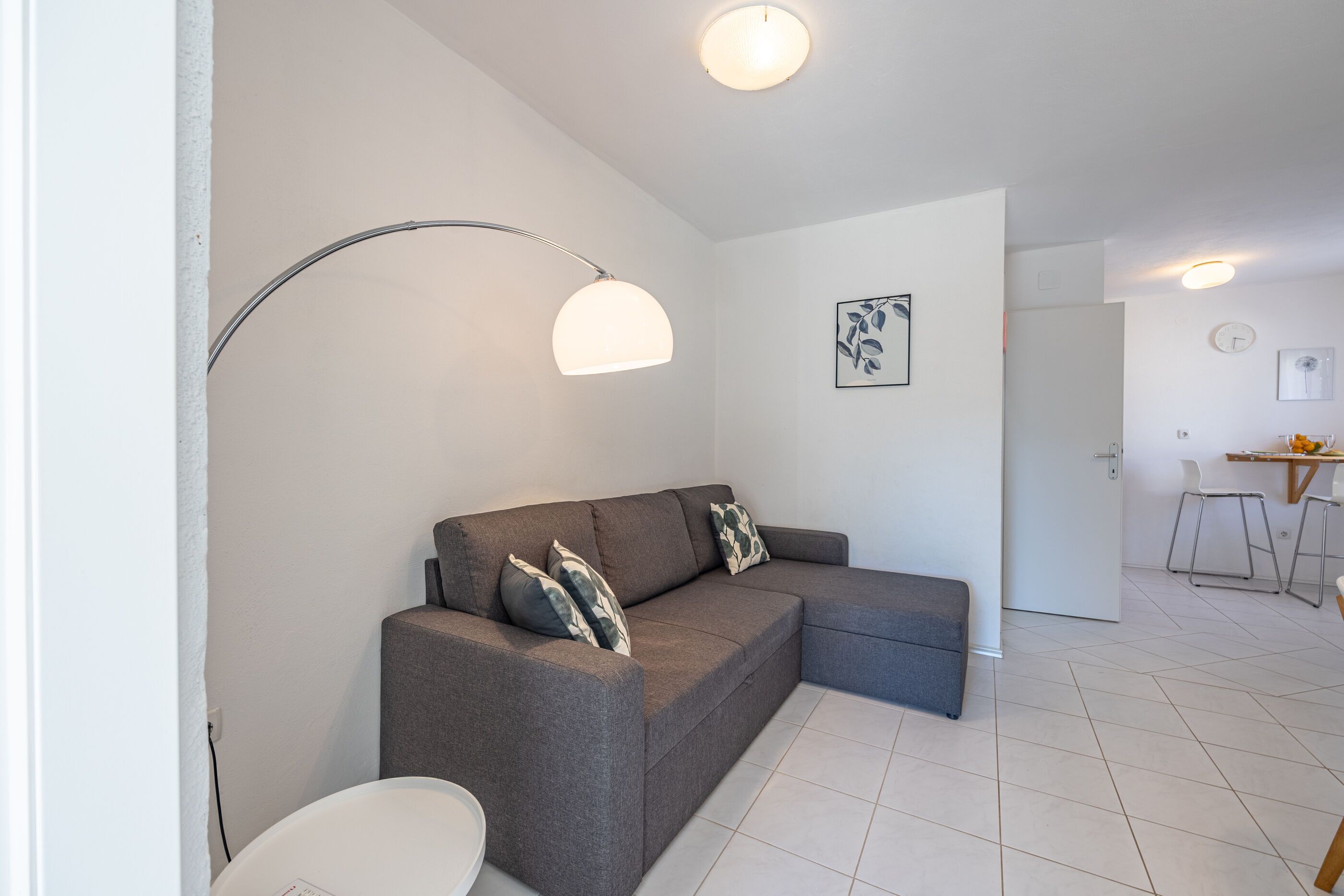 A modern living room with a grey sectional sofa, a white side table, and a floor lamp.