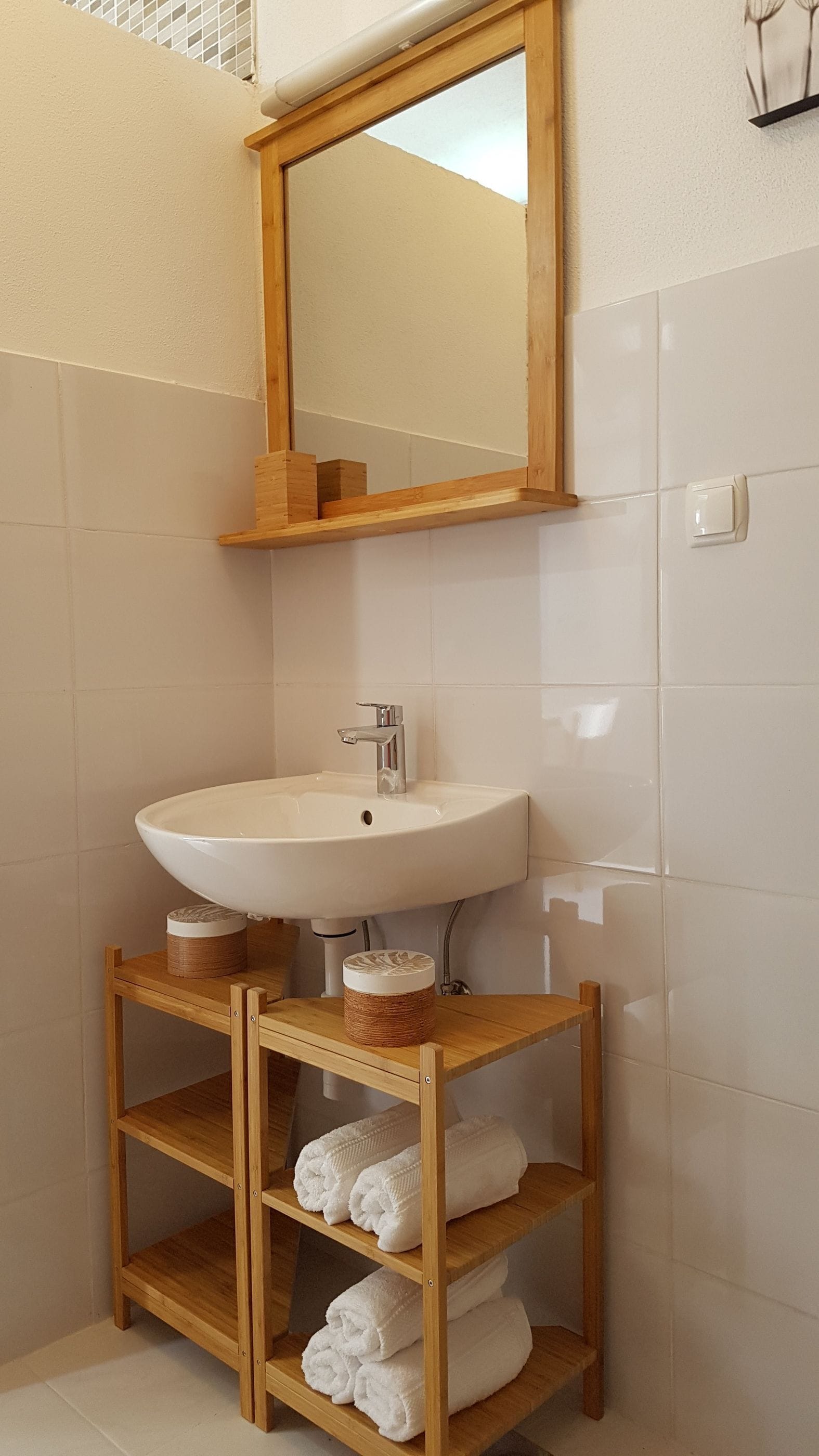 A bathroom with a white sink, wooden vanity, and a mirror.