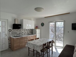 A modern kitchen with a dining area, featuring a built-in oven, a sink, and a dining table with chairs.