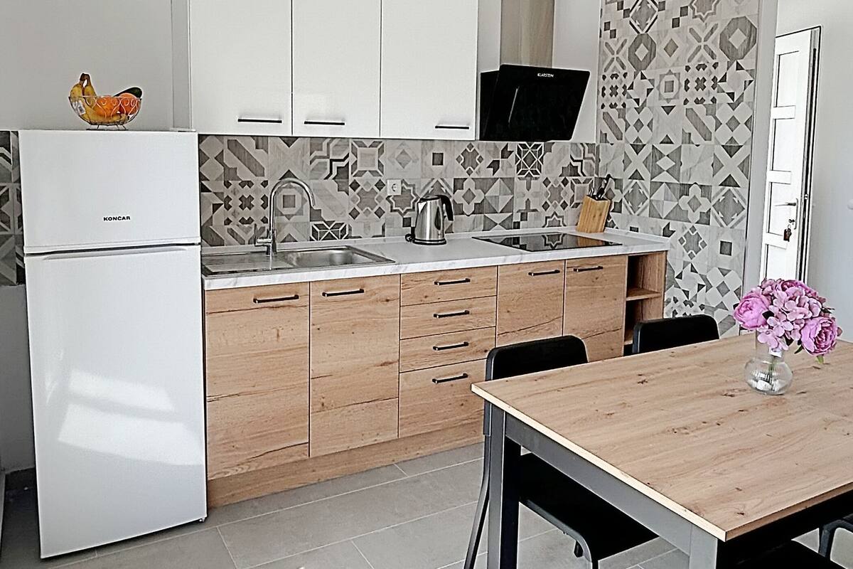 Eine moderne Küche mit einem weißen Kühlschrank, Holzschränken, einer Spüle und einer gefliesten Rückwand.