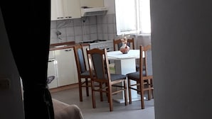 Eine Küche mit weißen Schränken, einem Herd und einem Esstisch mit Stühlen.
