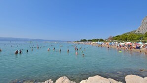 Une plage avec une eau claire, un rivage rocheux et des parasols.