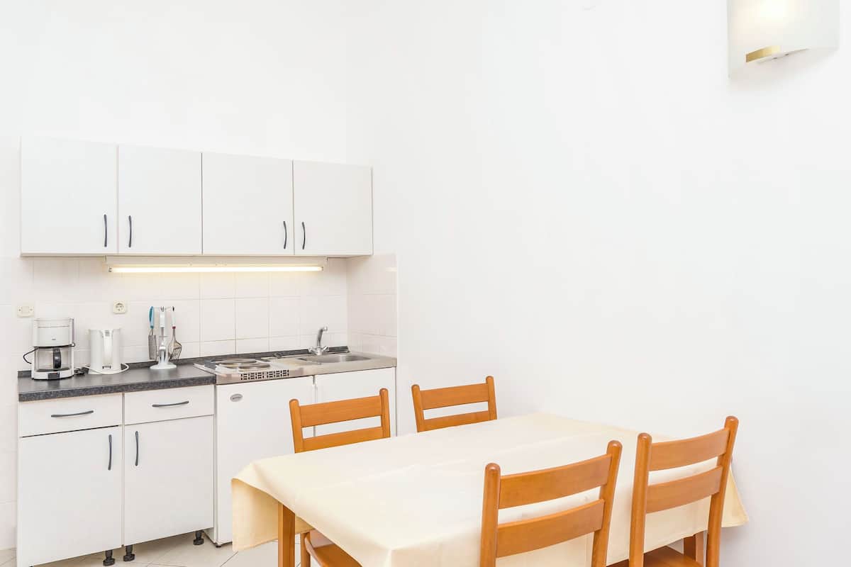A small kitchen with white cabinets, a sink, and a dining table with four chairs.