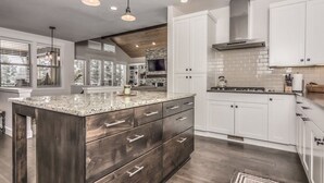 Cocina moderna con una isla grande, armarios blancos y salpicadero de piedra.