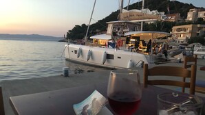 Une table avec un verre de vin rouge, un livre et un verre rempli de glaçons.