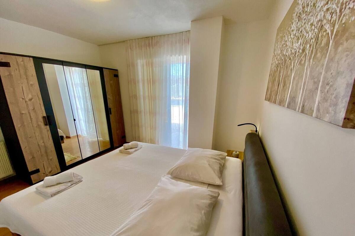 A hotel room with a large bed, a wardrobe with a mirror, and a painting on the wall.