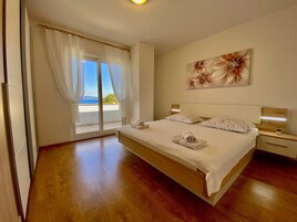 Un dormitorio con una cama grande, vistas a través de una puerta corrediza de vidrio y un cuadro en la pared.