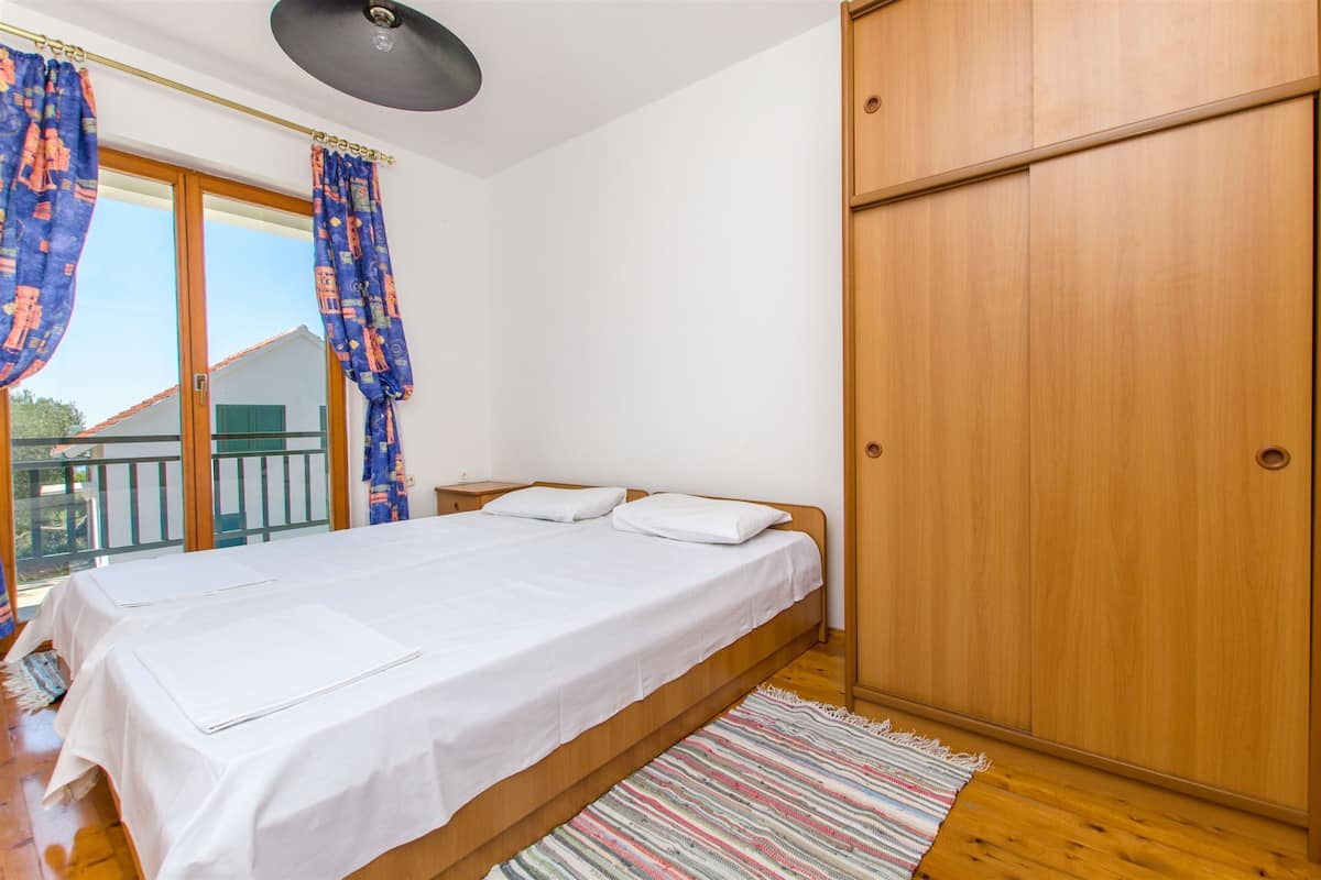 Une chambre à coucher avec un lit, une armoire en bois et un balcon avec des rideaux.