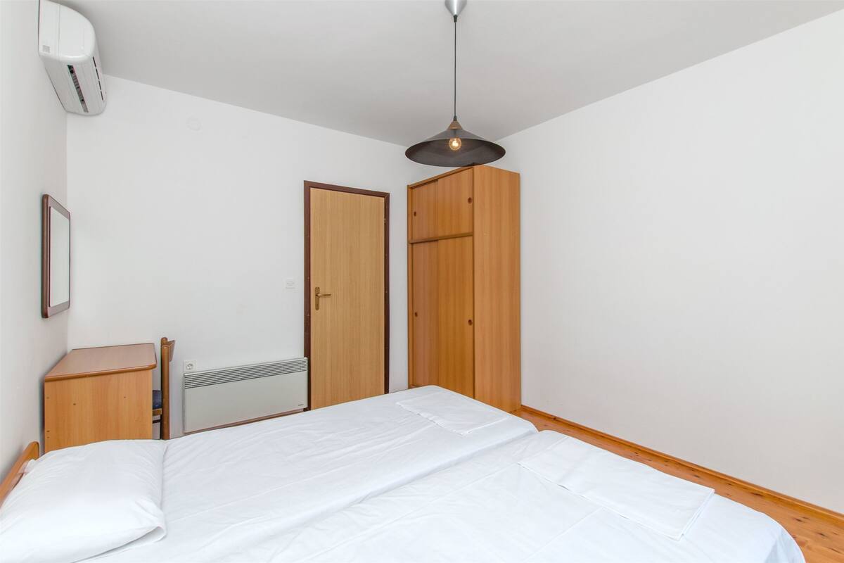 Une chambre à coucher comprenant un lit, une armoire, une table de chevet, un radiateur et un climatiseur.