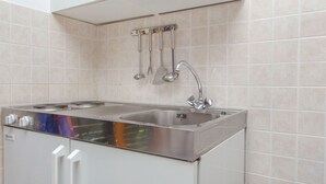 Une cuisine équipée d’un évier en acier inoxydable, d’une cuisinière et d’un porte-ustensiles.