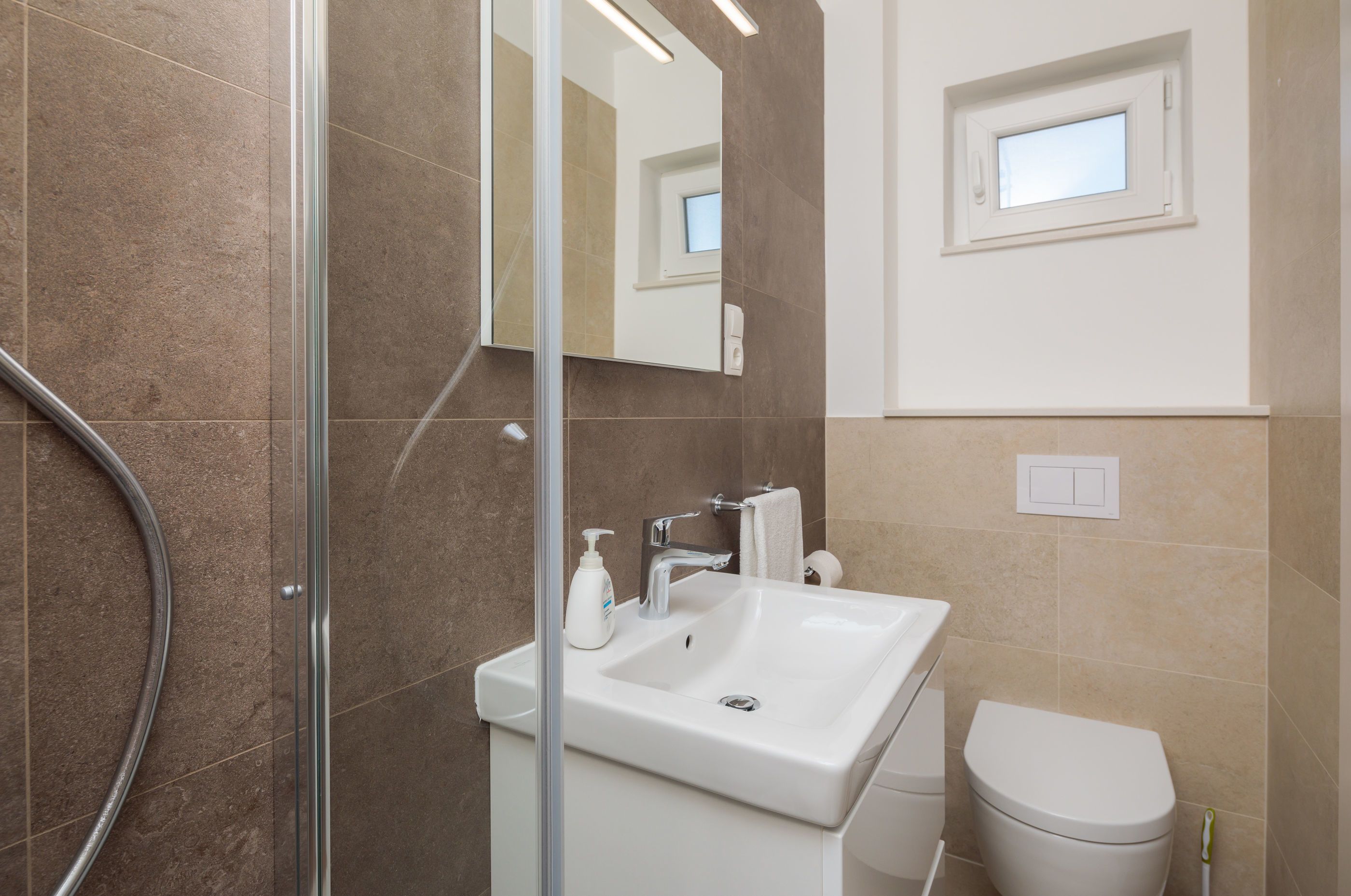 A modern bathroom with a glass shower enclosure, a white sink, and a toilet.