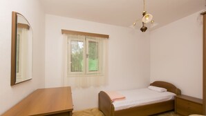 Une chambre à coucher avec un lit en bois, une table de chevet, un miroir, une fenêtre avec des rideaux et un luminaire au plafond.