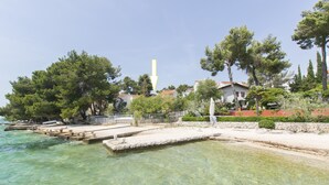 Une zone côtière caractérisée par une eau claire, une jetée et des immeubles résidentiels bordés d’arbres.