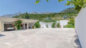 A parking area with a car, a building with a garage, and a mountainous backdrop.