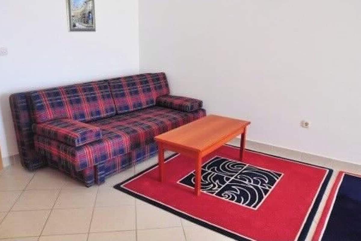 A room with a sofa, a small table, and a patterned rug.