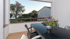 Ein Balkon mit Tisch, Stühlen und einer Blumenvase.
