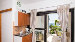 A compact kitchen with a sink, cabinets, and a window with curtains. - Apartments Danica (Murter)
