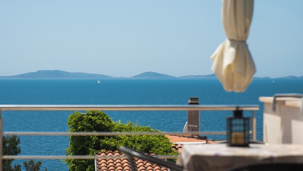 A balcony with a view of the sea, a sailboat, and distant mountains. - Apartments Danica (Murter)