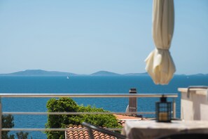 A balcony with a view of the sea, a sailboat, and distant mountains. - Apartments Danica (Murter)