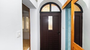 A hallway with a dark brown door, white walls, and a wooden door frame. - Apartments Danica (Murter)