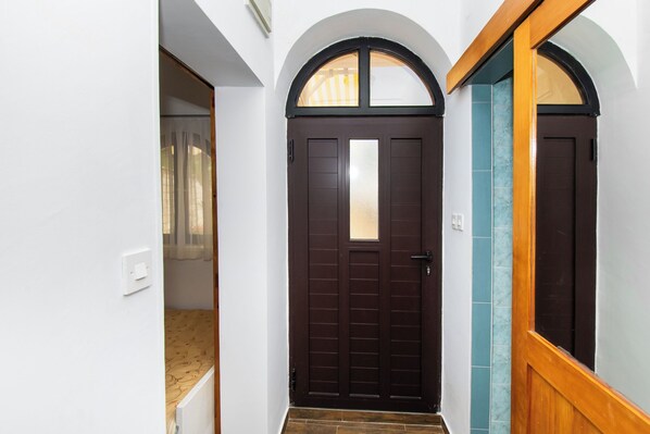 A hallway with a dark brown door, white walls, and a wooden door frame.