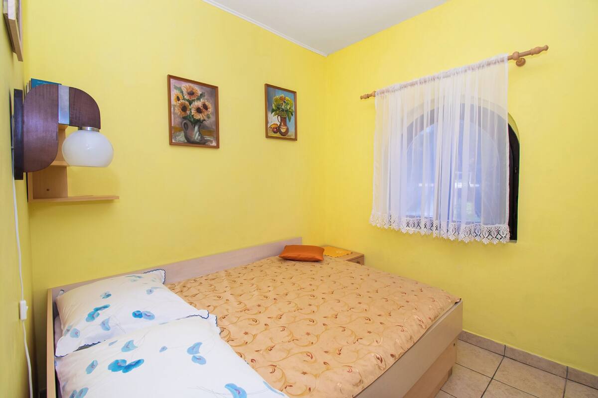 Une chambre à coucher avec un lit, une table de chevet, une lampe et deux tableaux accrochés au mur.