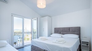 A bedroom with a bed, a wardrobe, a bedside table, and a balcony with a view. - Apartments Jozo (Stanici)