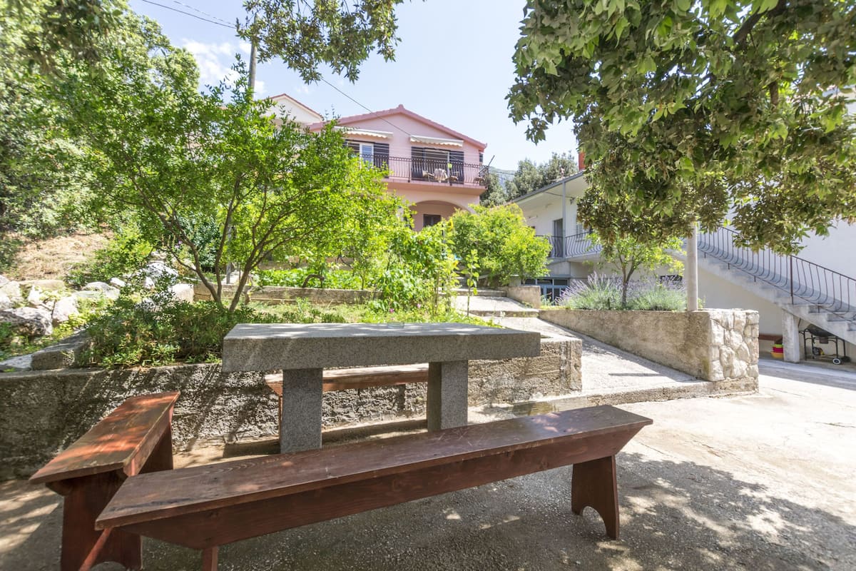 Une table et un banc en pierre, installés dans une cour, avec un bâtiment en arrière-plan.