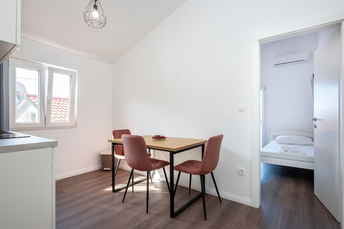 Une pièce de taille modeste comprenant une table à manger, deux chaises, un lit et un coin cuisine.