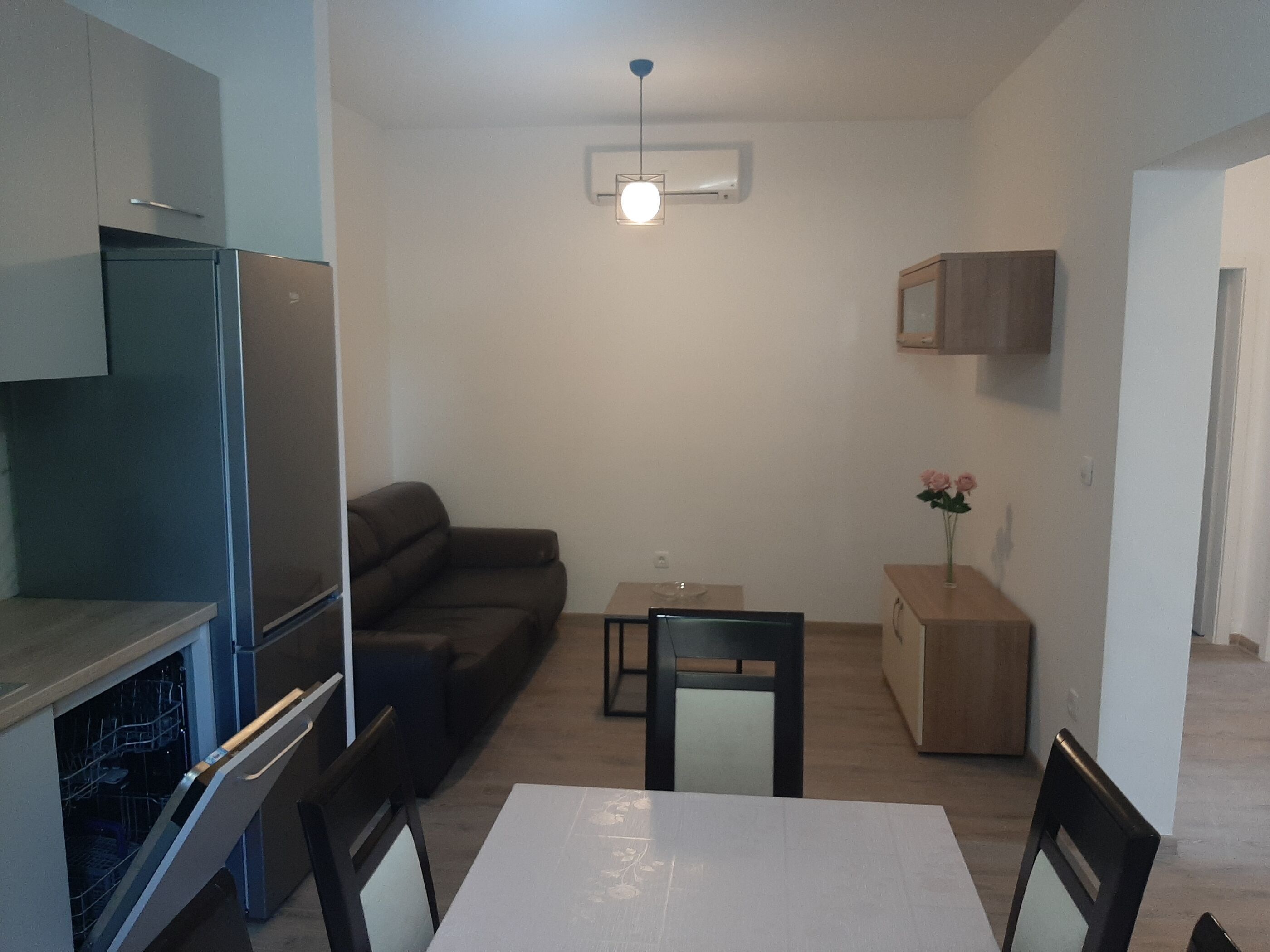 Una cocina compacta con refrigerador, lavavajillas y un comedor con mesa y sillas.
