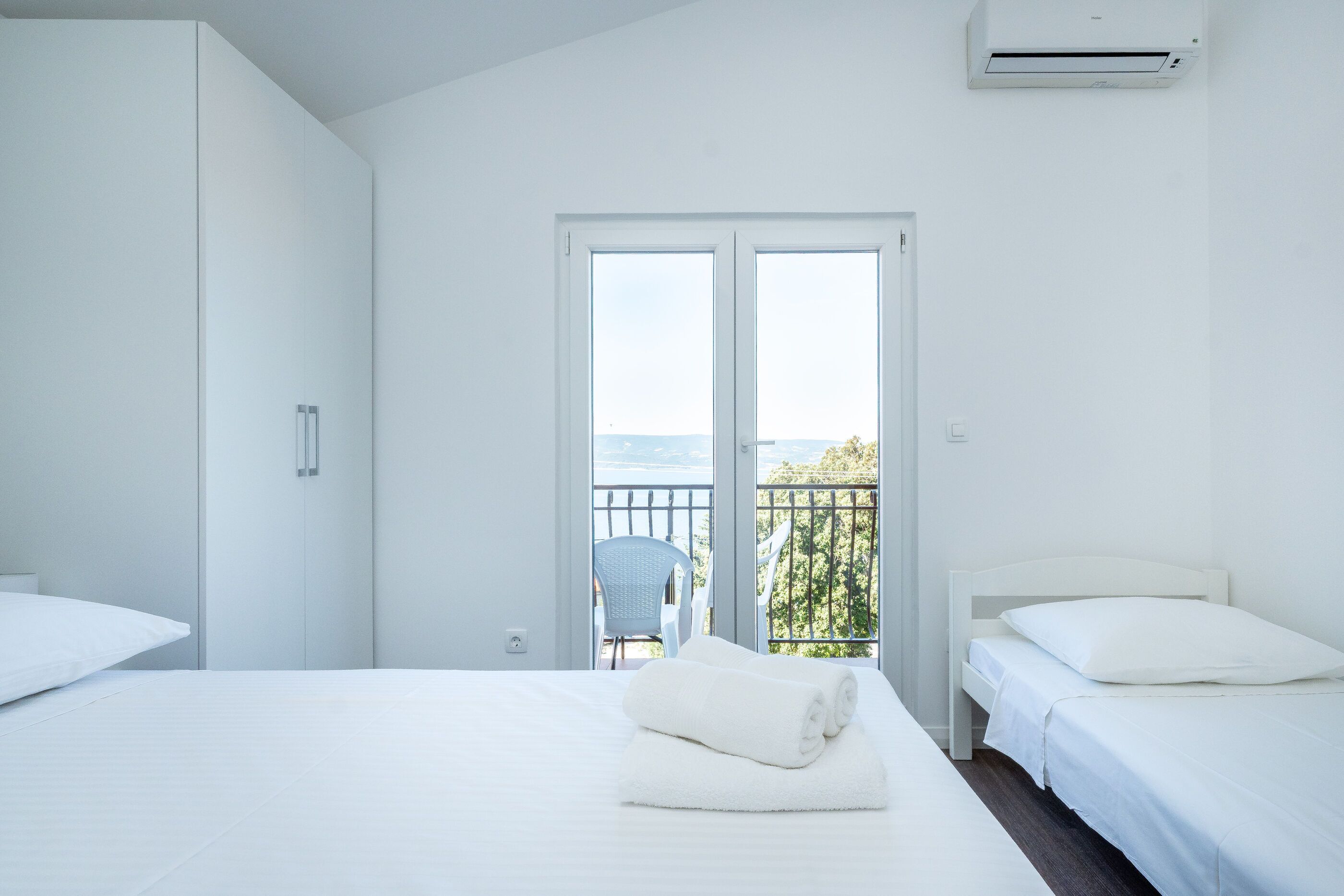 Habitación de hotel con cama, una silla y balcón con vistas.