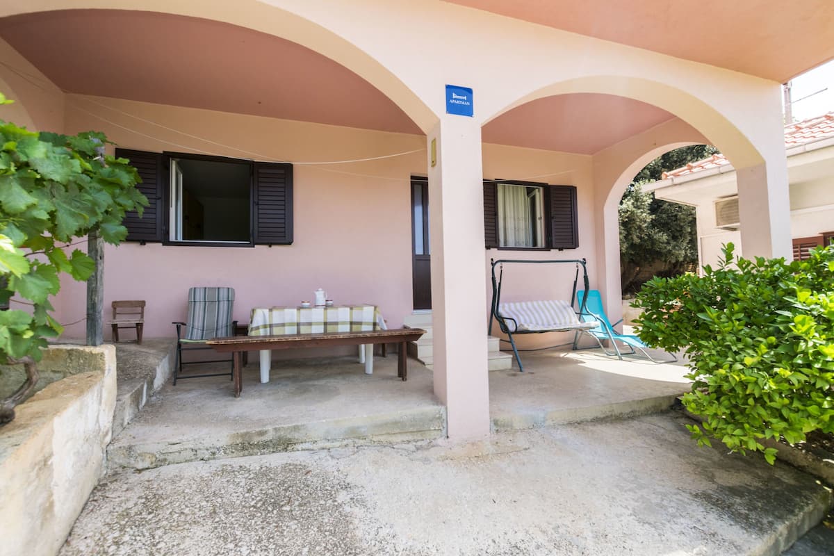 Un espace extérieur abrité avec un banc, une chaise et une balançoire.