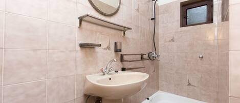A bathroom with a sink, mirror, shower, and bathtub.