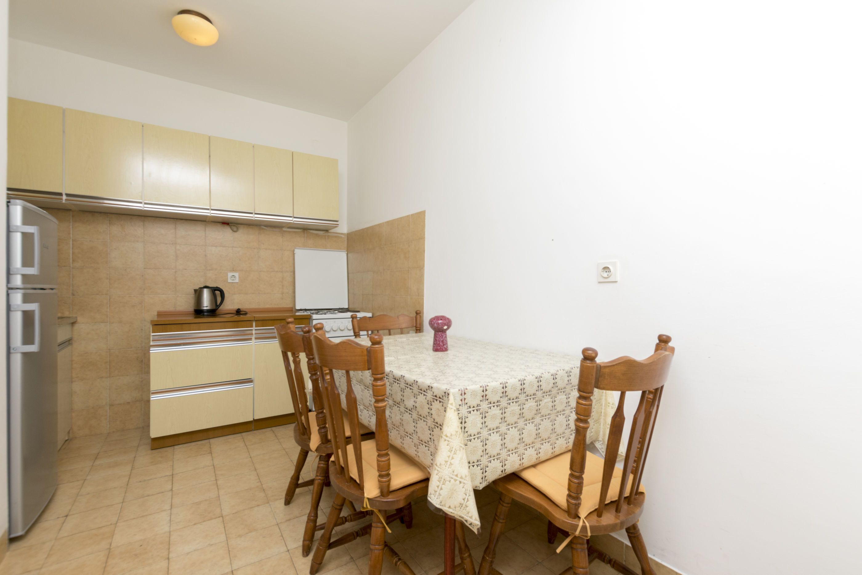 A compact kitchen with a dining table and chairs, a refrigerator, and a stove.
