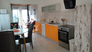 Uma cozinha moderna com armários laranja, uma pia de aço inoxidável e um forno embutido.