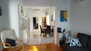 Uma sala de estar com sofá, poltrona, mesa de centro e área de jantar com cadeiras e mesa.