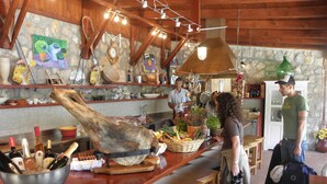 Une cuisine rustique avec un grand plafond en bois apparent, des murs en pierre et une variété d’ustensiles de cuisine et d’objets de décoration.