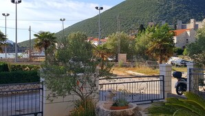 Une cour intérieure avec un mur en pierre, un portail en métal et un scooter garé près du portail.
