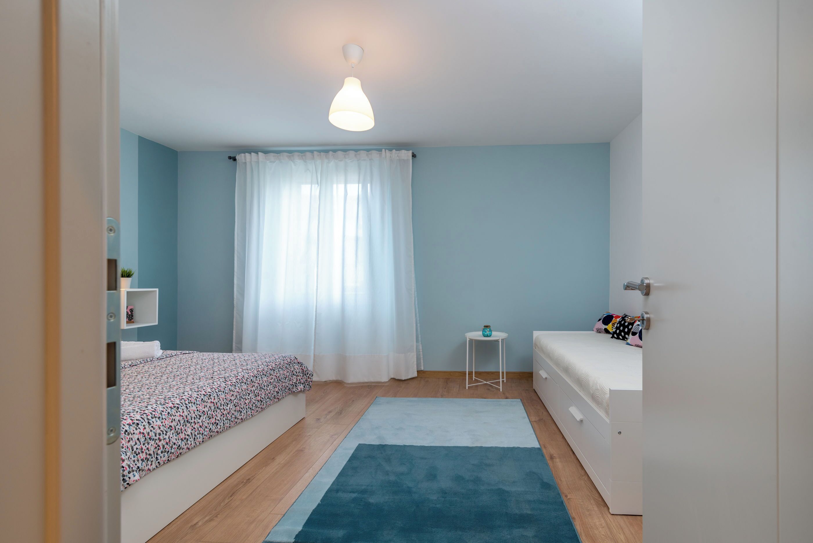 A bedroom with a bed, bedside table, and a small white dresser.