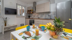 A modern kitchen with a dining table set for breakfast, including fruits and juice. - House Polus (Trogir)