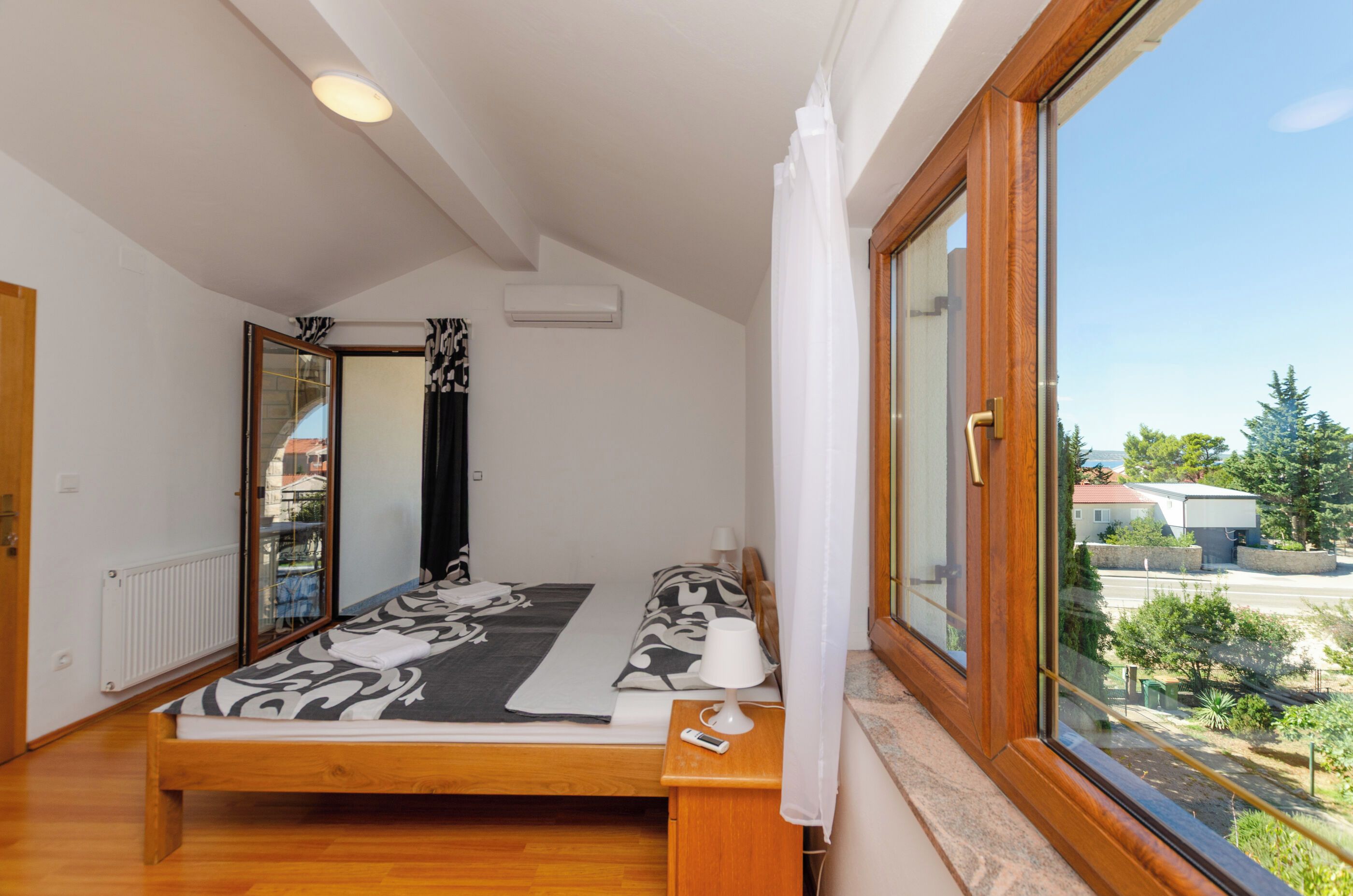 Un dormitorio con cama, ventana y vistas al exterior.