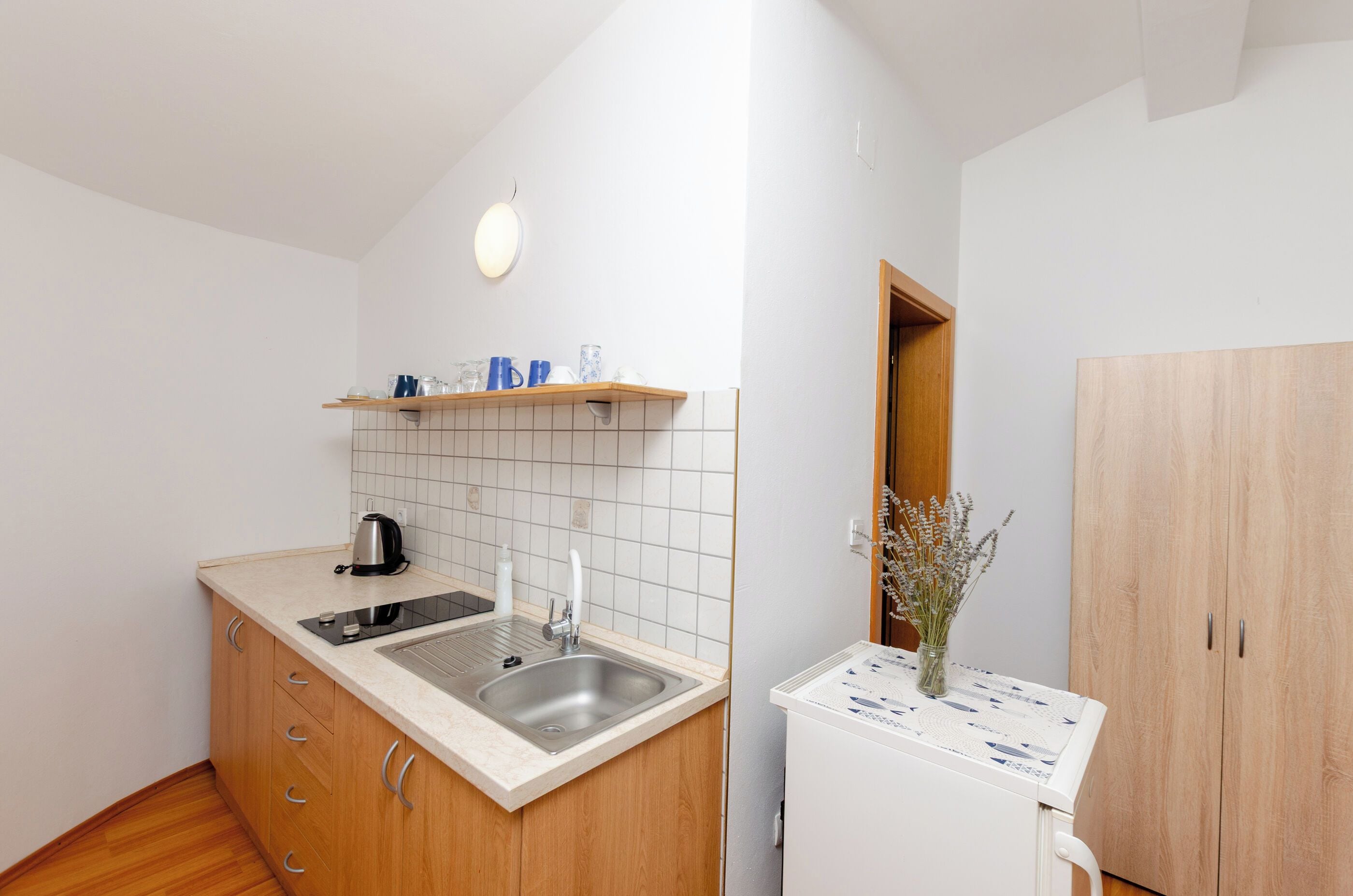 Cocina compacta con estufa integrada, un lavamanos y un mueble de madera con cajones.